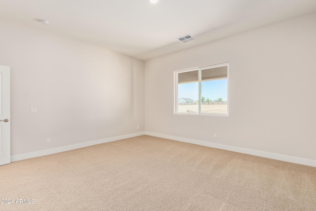 unfurnished room with carpet floors, visible vents, and baseboards