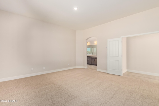 empty room with recessed lighting, baseboards, arched walkways, and light colored carpet