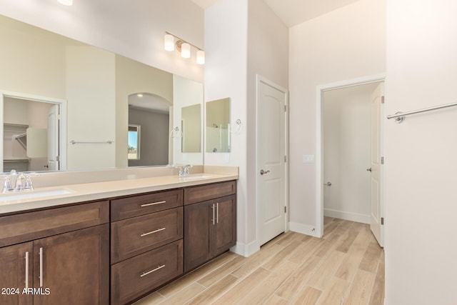 full bathroom with a closet, double vanity, a sink, and wood finished floors