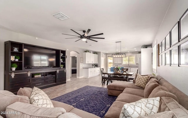 living room featuring arched walkways, visible vents, ceiling fan, and wood finished floors