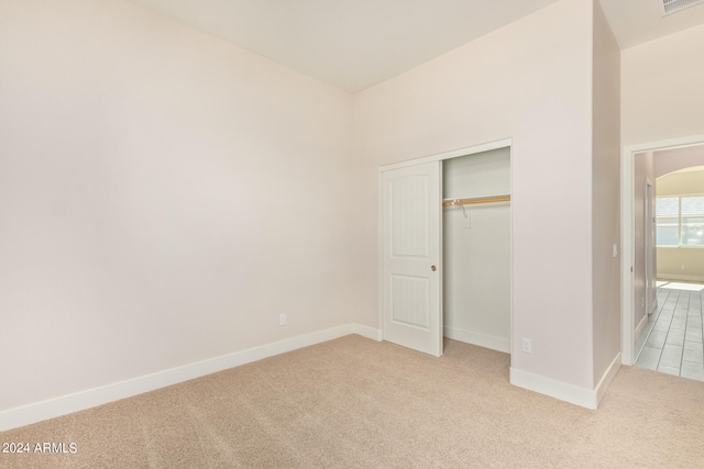 unfurnished bedroom featuring light carpet, visible vents, baseboards, and a closet