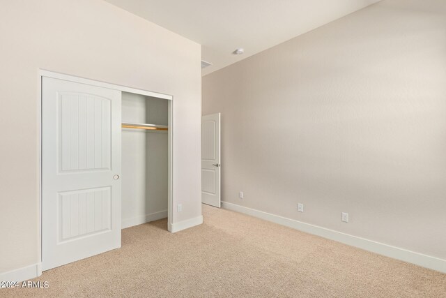 unfurnished bedroom with baseboards, a closet, and light colored carpet