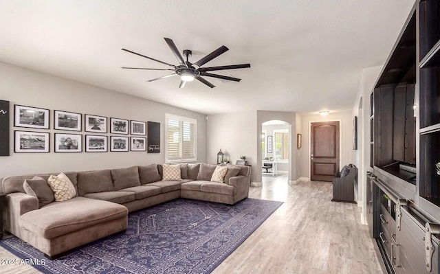 living room featuring arched walkways, light wood-type flooring, and a ceiling fan