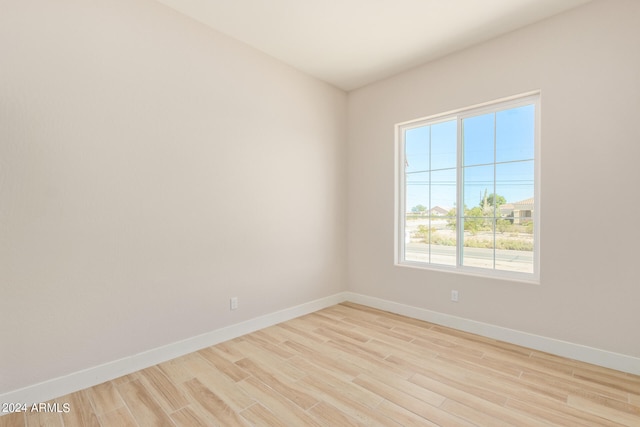 spare room featuring light wood finished floors and baseboards