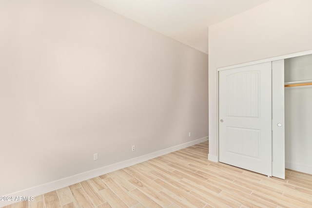 unfurnished bedroom with a closet, light wood-style flooring, and baseboards