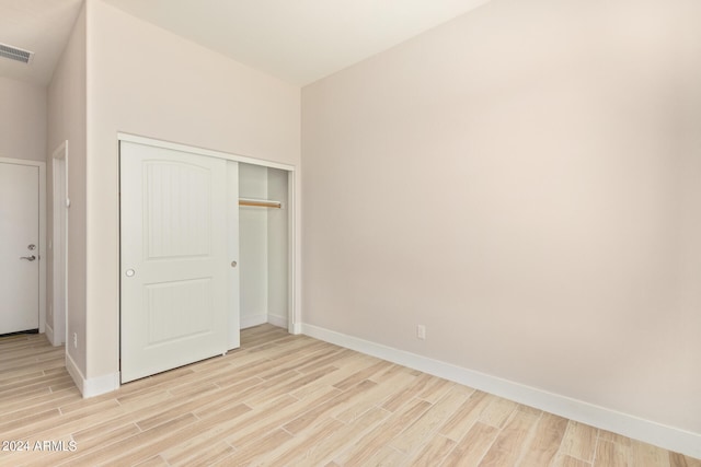 unfurnished bedroom featuring light wood-style flooring, visible vents, baseboards, and a closet