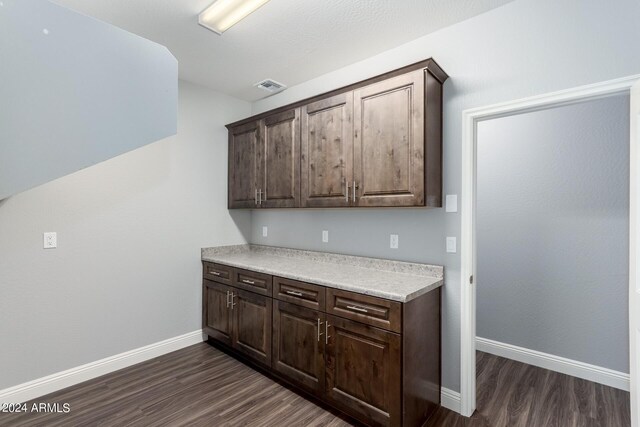 kitchen featuring dark brown cabinetry, dark wood-style floors, and light countertops