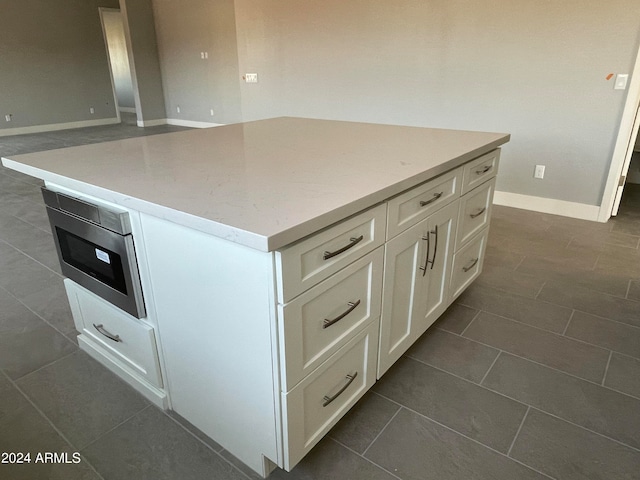 kitchen featuring stainless steel microwave, a kitchen island, and white cabinetry