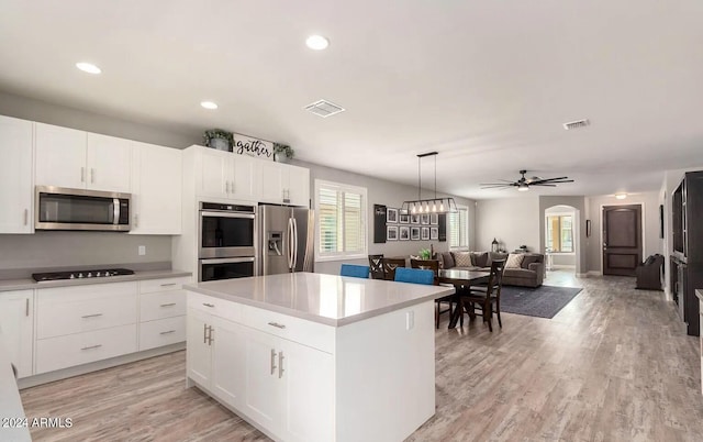 kitchen featuring stainless steel appliances, visible vents, white cabinets, light countertops, and a center island