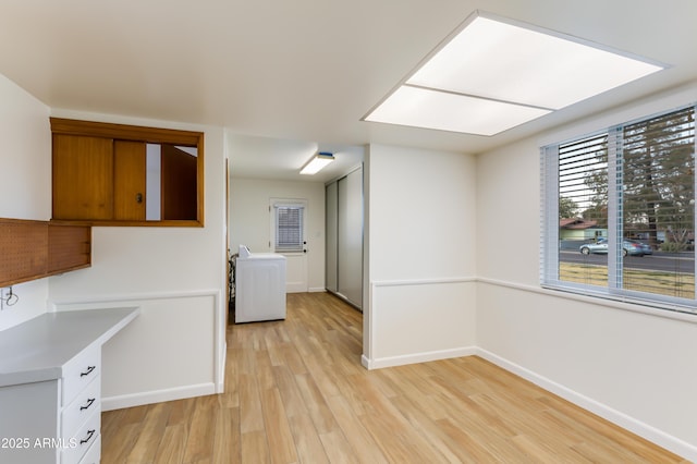 kitchen with white cabinetry, light hardwood / wood-style flooring, and washer / dryer