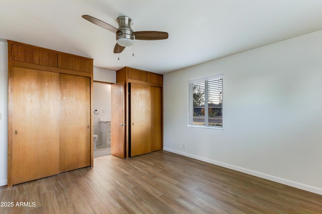 unfurnished bedroom with hardwood / wood-style floors, ceiling fan, and ensuite bath