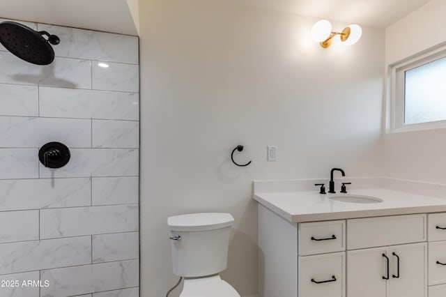 bathroom featuring a tile shower, vanity, and toilet