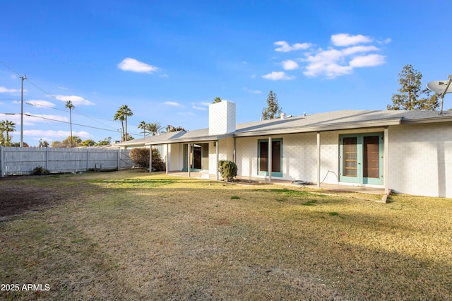 rear view of house featuring french doors, a patio, and a lawn