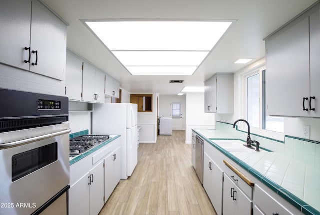 kitchen featuring tile counters, white cabinets, and stainless steel appliances