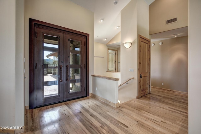 foyer featuring lofted ceiling, french doors, and light wood-type flooring