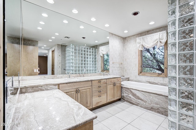 bathroom with a relaxing tiled tub, vanity, and tile patterned floors