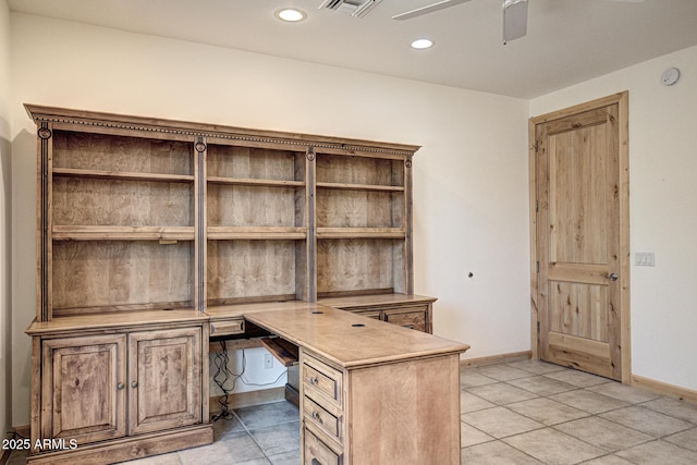 unfurnished office with built in desk, ceiling fan, and light tile patterned floors