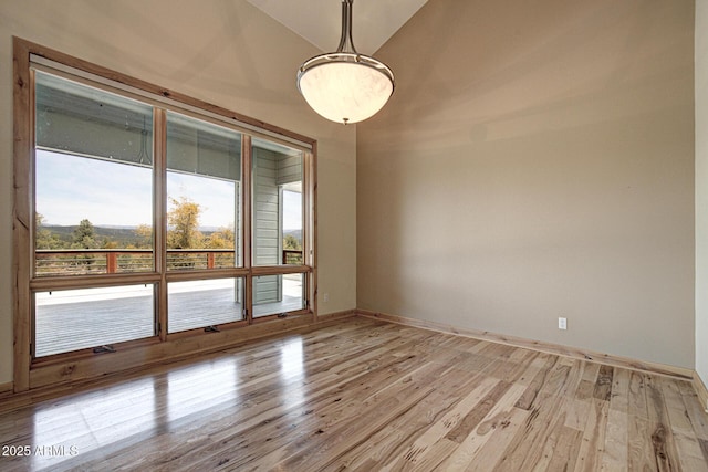 spare room featuring lofted ceiling and light hardwood / wood-style floors