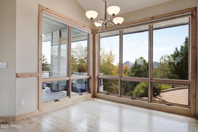 unfurnished sunroom with an inviting chandelier, a mountain view, plenty of natural light, and lofted ceiling