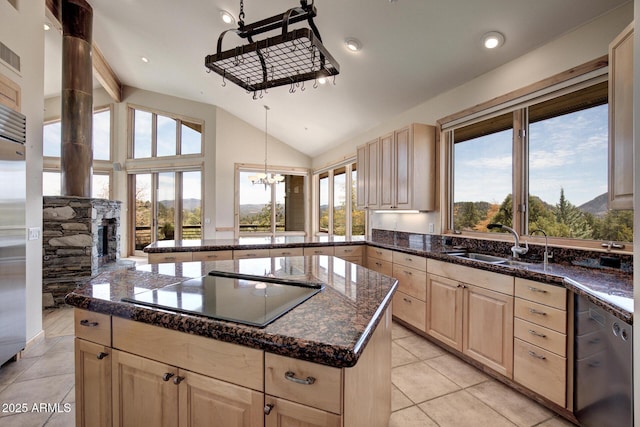 kitchen with sink, black electric stovetop, a healthy amount of sunlight, a kitchen island, and a stone fireplace