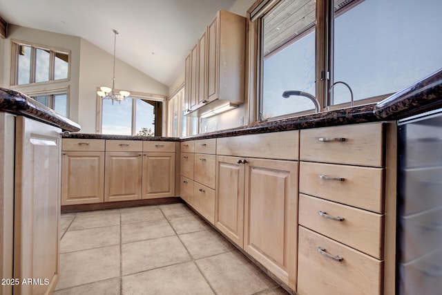 kitchen with hanging light fixtures, vaulted ceiling, light brown cabinets, and dark stone counters