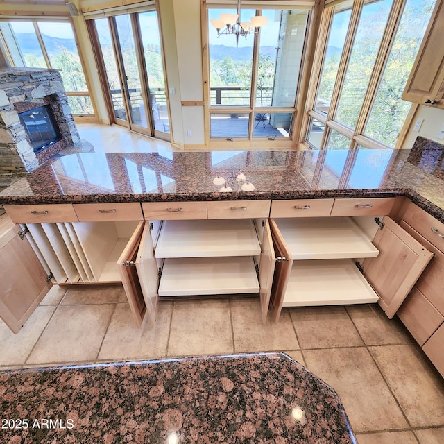 kitchen with a fireplace, a wealth of natural light, and dark stone counters