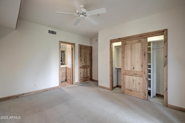 unfurnished bedroom with ceiling fan, light carpet, and ensuite bath