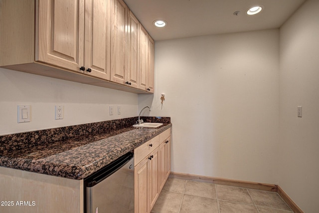 kitchen with sink, light tile patterned floors, stainless steel dishwasher, and dark stone counters