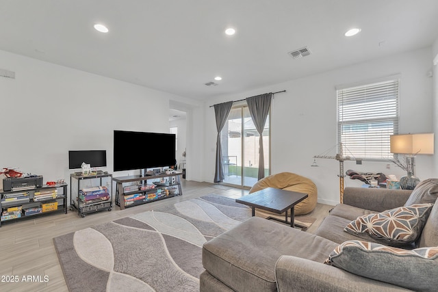 living area with light wood-style flooring, visible vents, and recessed lighting