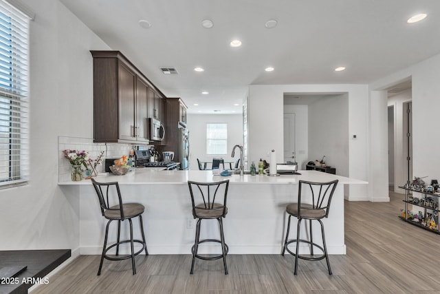 kitchen with a peninsula, range, stainless steel microwave, and light countertops