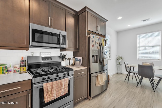 kitchen with dark brown cabinetry, visible vents, light countertops, appliances with stainless steel finishes, and tasteful backsplash