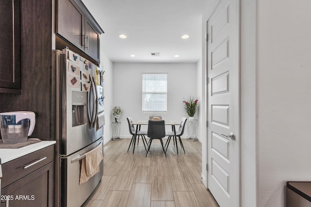 kitchen featuring recessed lighting, light countertops, dark brown cabinetry, and stainless steel refrigerator with ice dispenser