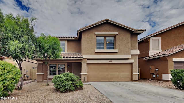 view of front of house with an attached garage, a tile roof, concrete driveway, and stucco siding