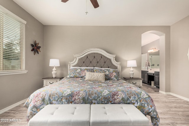 1078 W Redwood Ave, Queen Creek, AZ 85140 - bedroom with arched walkways, baseboards, light wood-style floors, and connected bathroom