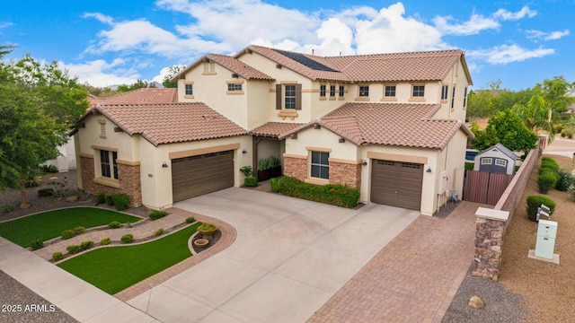 mediterranean / spanish house featuring stucco siding, driveway, fence, and stone siding