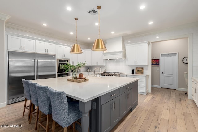 kitchen with stainless steel appliances, custom exhaust hood, gray cabinets, white cabinets, and crown molding