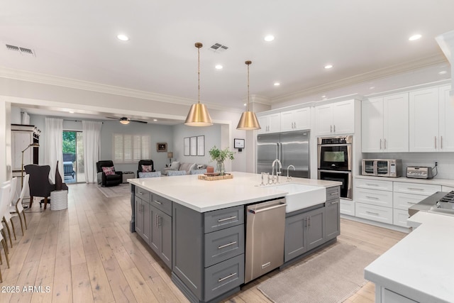 kitchen with gray cabinetry, stainless steel appliances, a sink, white cabinetry, and ornamental molding