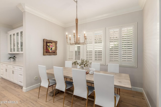 dining space featuring a chandelier, ornamental molding, light wood-style floors, and baseboards