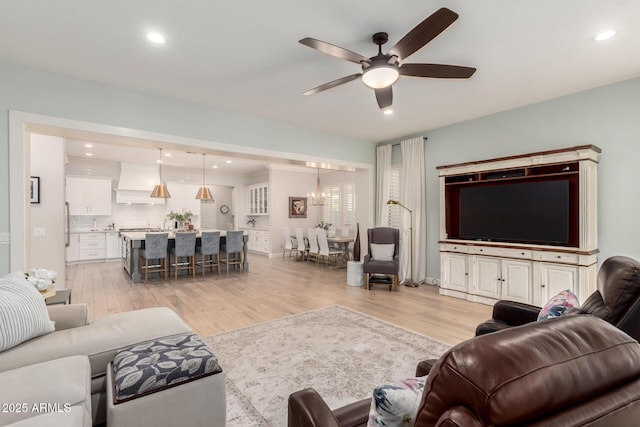 living room with light wood-style flooring, a ceiling fan, and recessed lighting