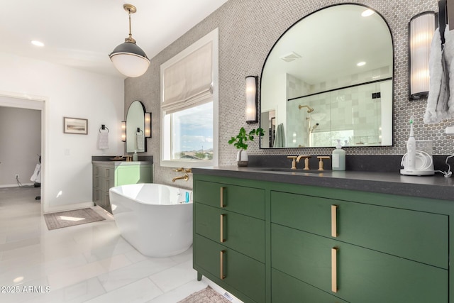 bathroom with a shower stall, a freestanding bath, two vanities, and baseboards