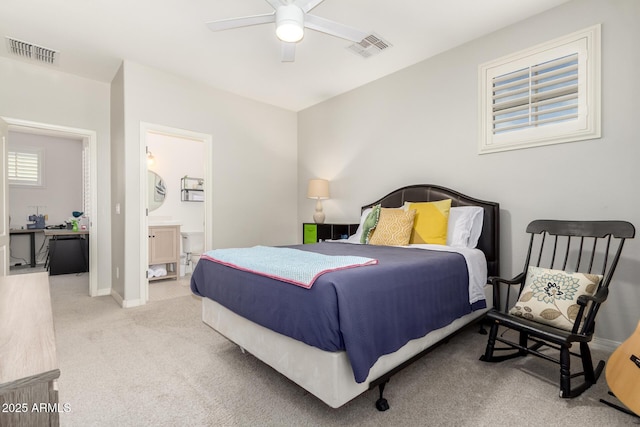 carpeted bedroom with ensuite bath, baseboards, and a ceiling fan