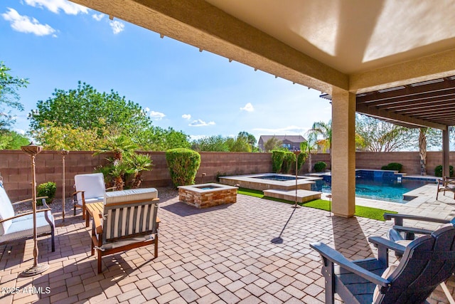 view of patio / terrace with an in-ground hot tub, a fenced backyard, and an outdoor fire pit