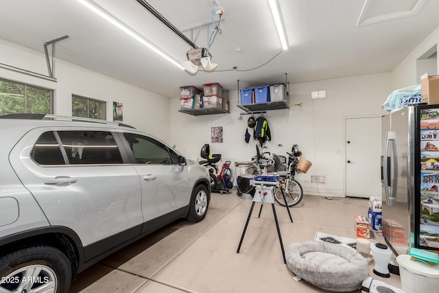 garage with a garage door opener and stainless steel refrigerator with ice dispenser