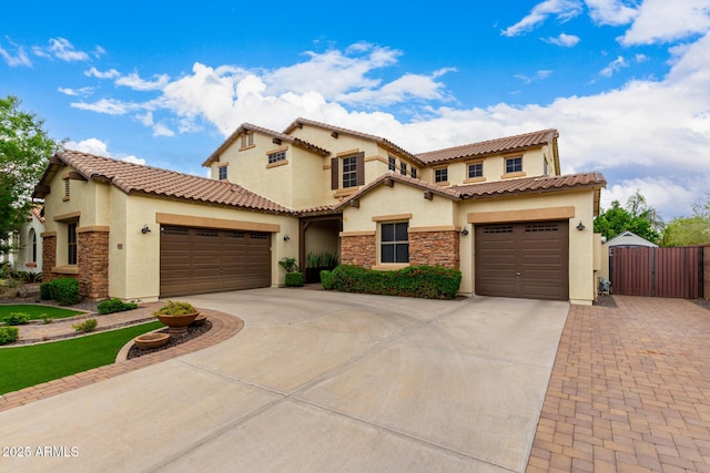 mediterranean / spanish-style home featuring concrete driveway, stucco siding, stone siding, and a garage