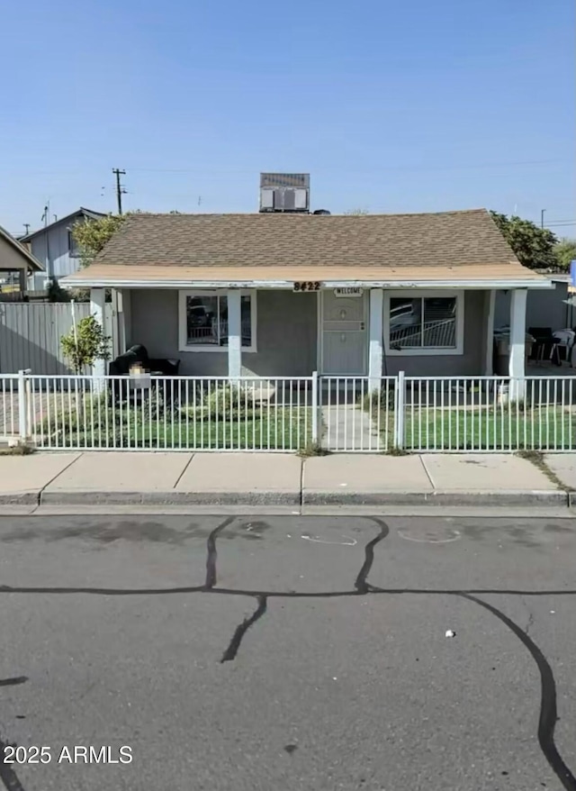 view of front of home with a fenced front yard and roof with shingles
