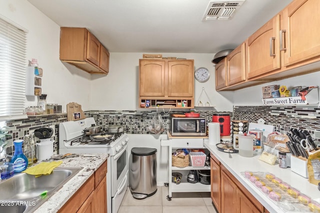 kitchen with light countertops, stainless steel microwave, visible vents, a sink, and white gas range oven