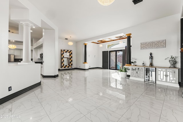 10417 N 180th Dr, Waddell, AZ 85355 - living area with wine cooler, marble finish floor, decorative columns, and baseboards