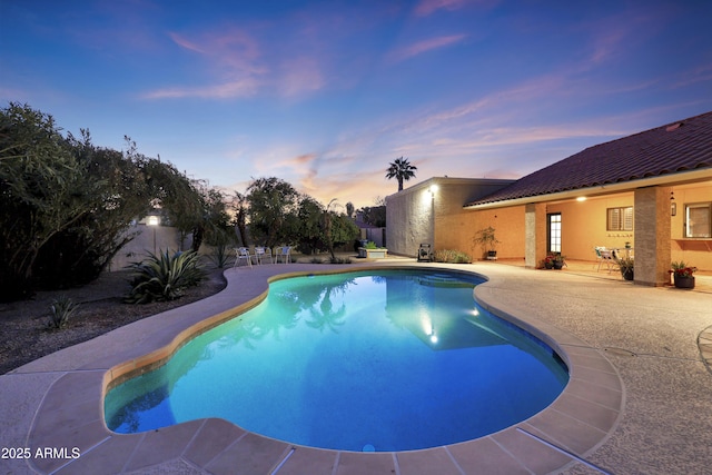 pool at dusk with a patio area