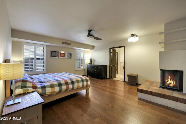 bedroom with ceiling fan, a fireplace, and hardwood / wood-style flooring