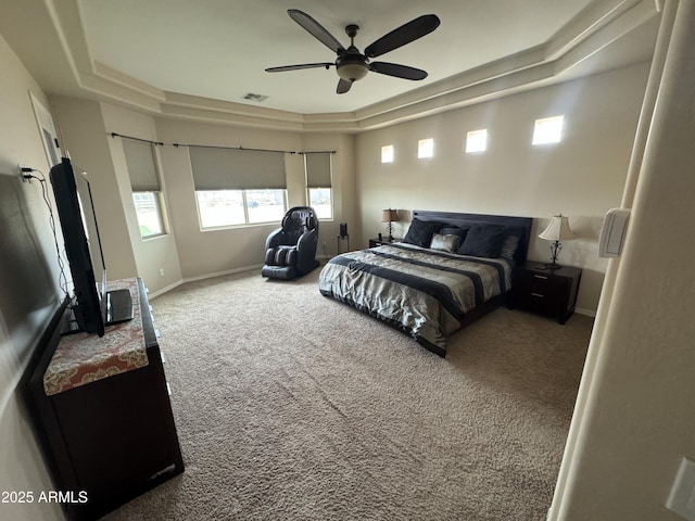 carpeted bedroom with visible vents, baseboards, a raised ceiling, and a ceiling fan